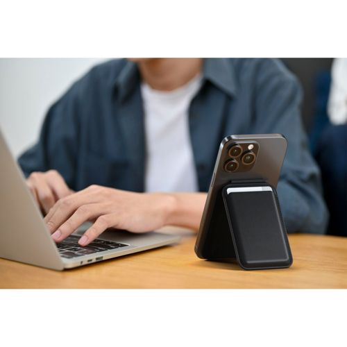 Un uomo digita su un laptop, con uno smartphone su un supporto nero accanto.