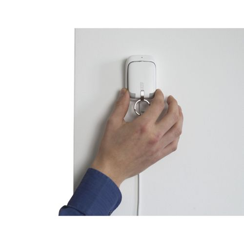 Una mano tiene un piccolo dispositivo bianco con un portachiavi su un muro bianco.