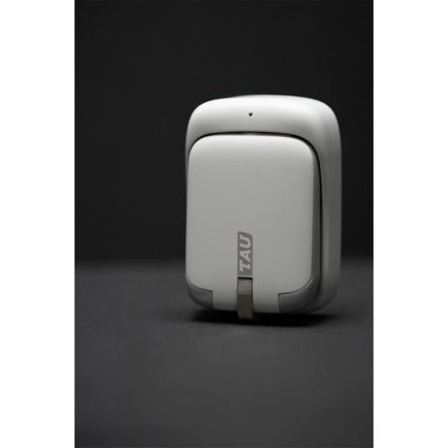 Un piccolo dispositivo bianco con la scritta "TAU" si trova su sfondo scuro.
