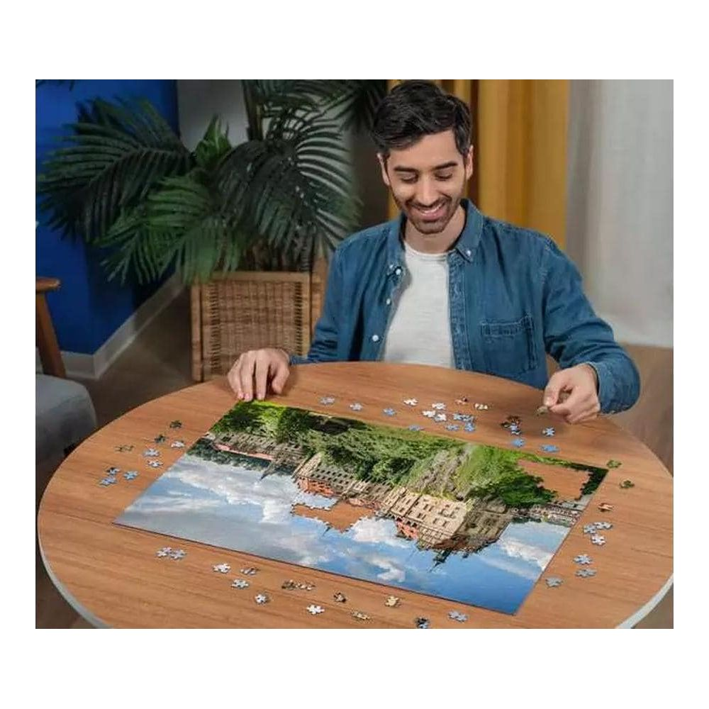 Uomo che assembla un puzzle raffigurante un edificio sull'acqua.