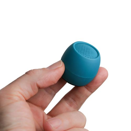 Une main tient un petit haut-parleur bleu sarcelle, en forme d'œuf, avec un dessus perforé.