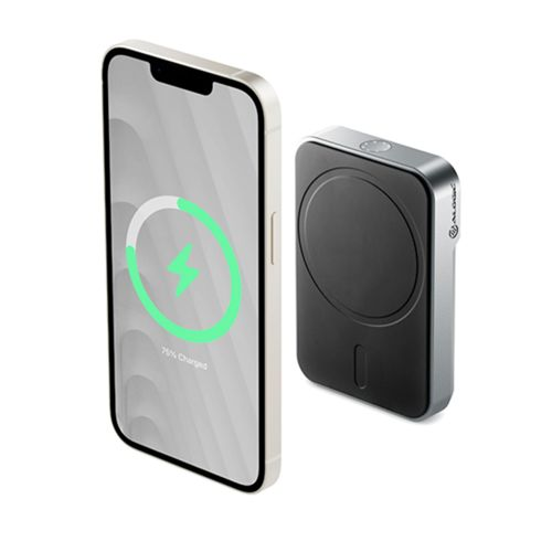 Un iPhone argentato accanto a un caricatore magnetico nero.