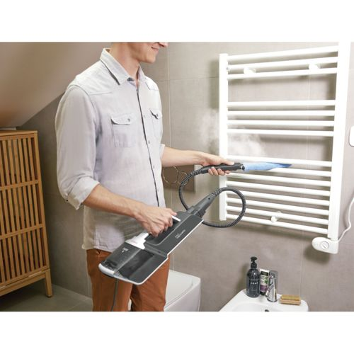 Uomo pulisce termosifone con pulitore a vapore in bagno.