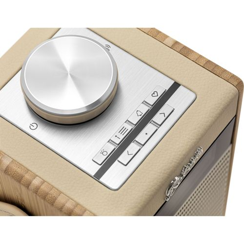 Gros plan d'une radio avec cadran argenté, boutons et cuir crème.