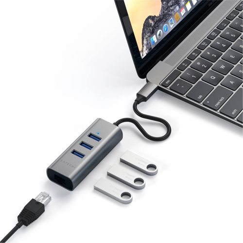 Un concentrador USB gris conectado a un portátil. Tres memorias USB al lado.