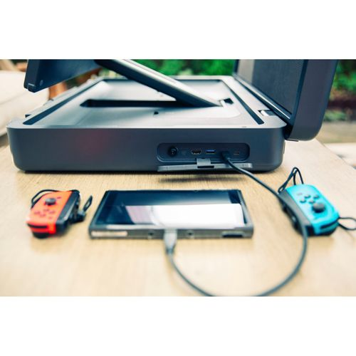 Ein schwarzes Dock steht auf einem Holztisch mit roten und blauen Joy-Cons.