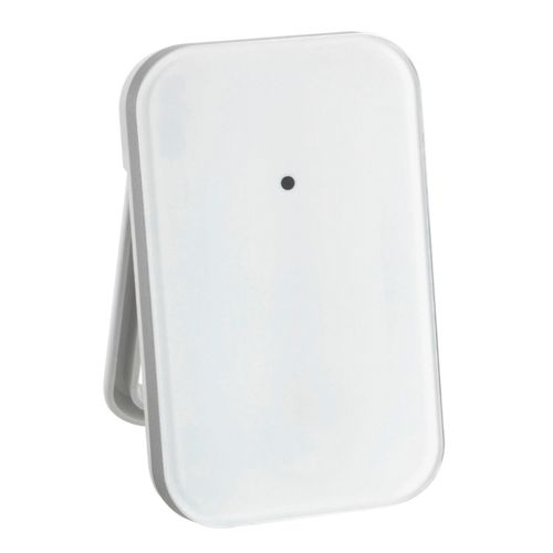 Un appareil blanc et rectangulaire avec un petit point noir est soutenu par un support gris.