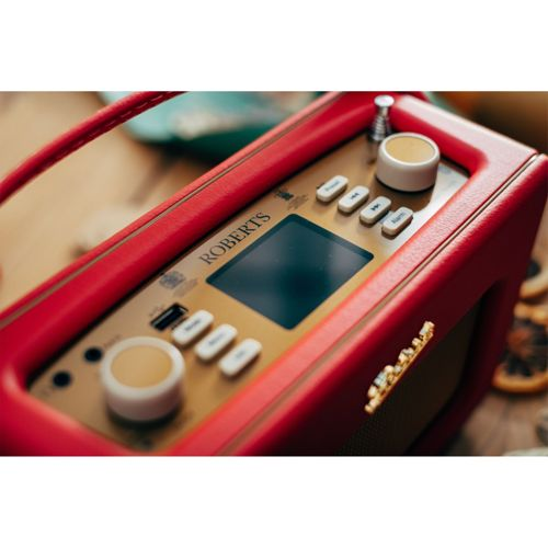 Ein rotes Roberts Radio mit goldenem Bedienfeld, Knöpfen und einem Bildschirm.