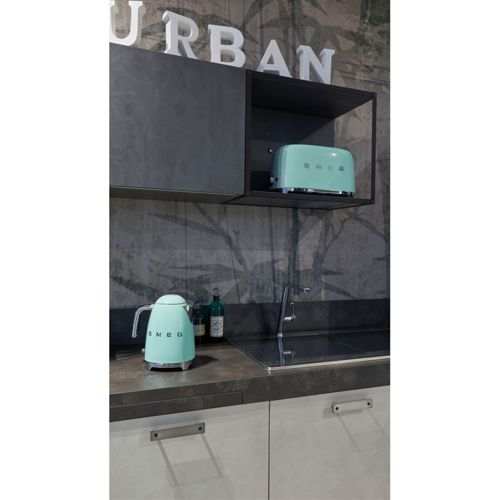 Una tetera Smeg verde menta y una tostadora sobre un mostrador de cocina con pared de bambú.