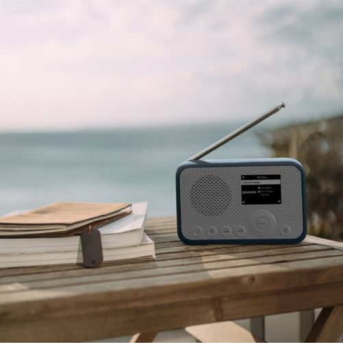 Een radio en boeken op een houten tafel aan zee.