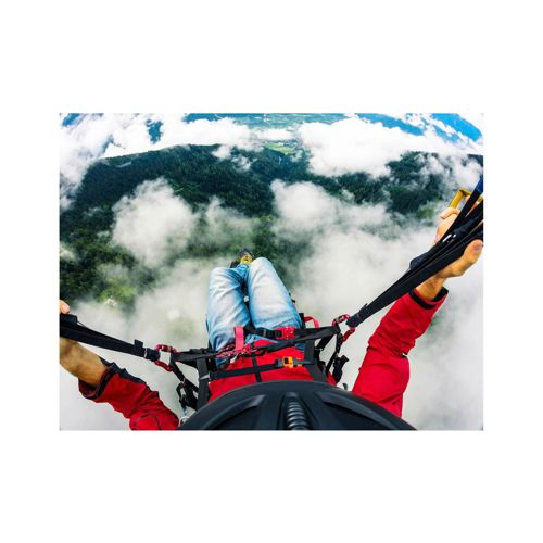 POV parapendio in giacca rossa, jeans blu, che vola su foresta e nuvole.