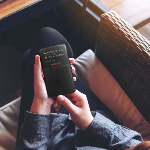 A person holds a small black radio with a screen.