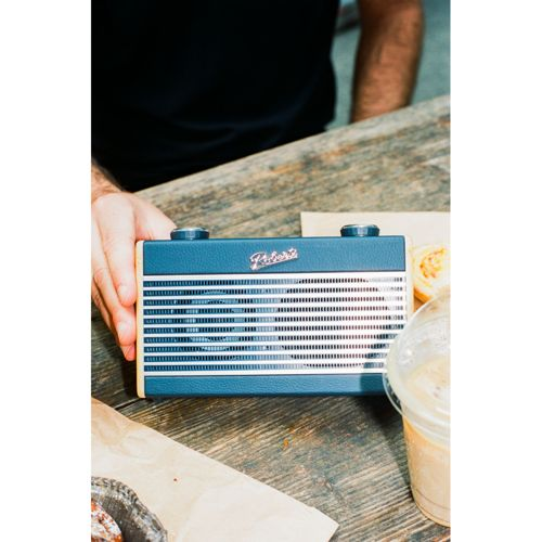 Une radio rétro bleue à rayures argentées sur une table en bois.