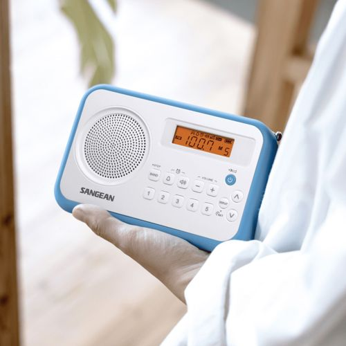 Una persona tiene una radio Sangean blu e bianca con schermo LCD e pulsanti.