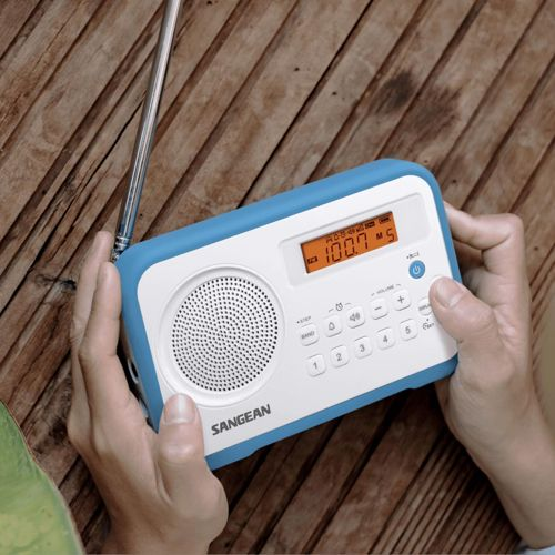 Mani che tengono una radio blu e bianca con antenna su un tavolo di legno.