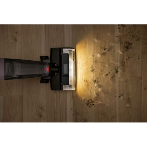 Ein Staubsauger reinigt einen Holzboden mit Schmutz und Haaren.