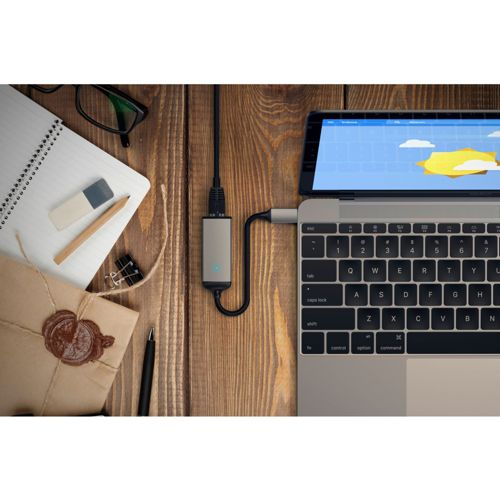 Un laptop è collegato tramite adattatore e cavo. Cancelleria nelle vicinanze su una scrivania di legno.