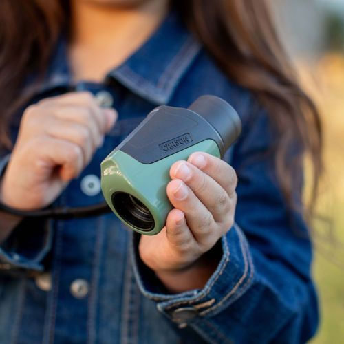 Un bambino con giacca di jeans tiene un monocolo Carson verde e nero.