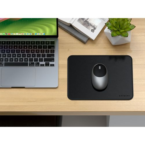 Ein silberner Laptop mit Tastatur und ein silberner Maus auf einer schwarzen Unterlage.