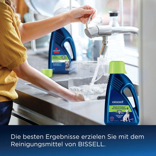 Una persona llena un recipiente con agua, junto a limpiador BISSELL.