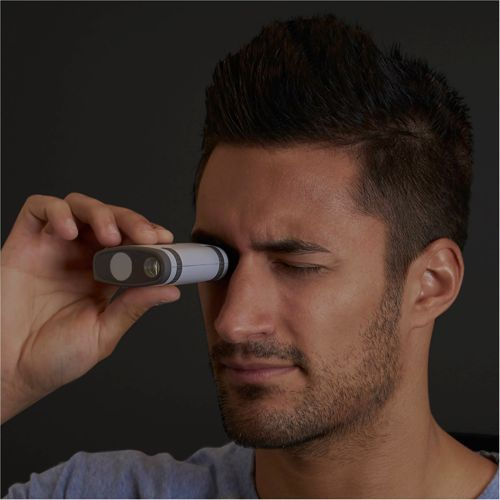 Uomo guarda in un piccolo dispositivo bianco e grigio tenuto all'occhio destro.