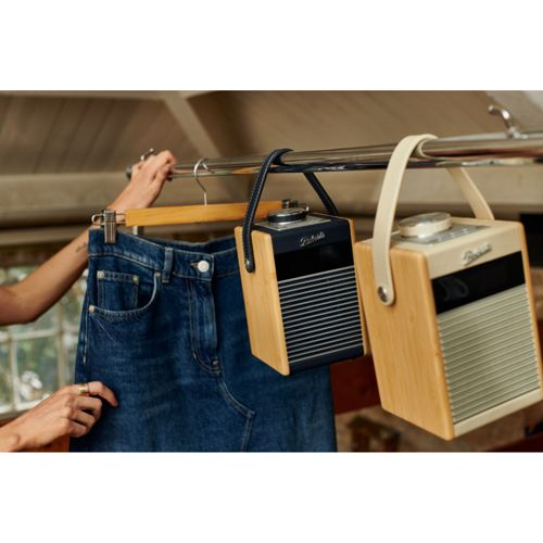 Eine Hand hängt eine Jeans an eine Stange. Zwei Radios hängen daneben.