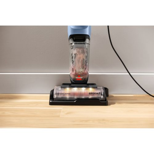 Ein Bissell Bodenreiniger mit blauem Tank und LED-Leuchten auf Holzboden.