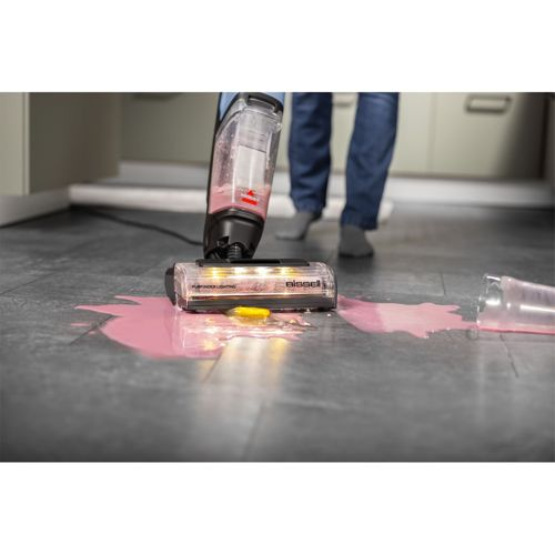 Bodenreiniger mit rosa Flüssigkeit auf dem Boden, ein Becher ist umgefallen.