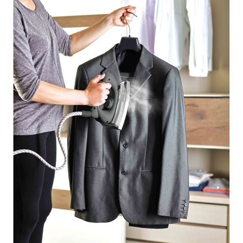 Person dampft einen grauen Anzug mit einem Handdampfer im Schrank.