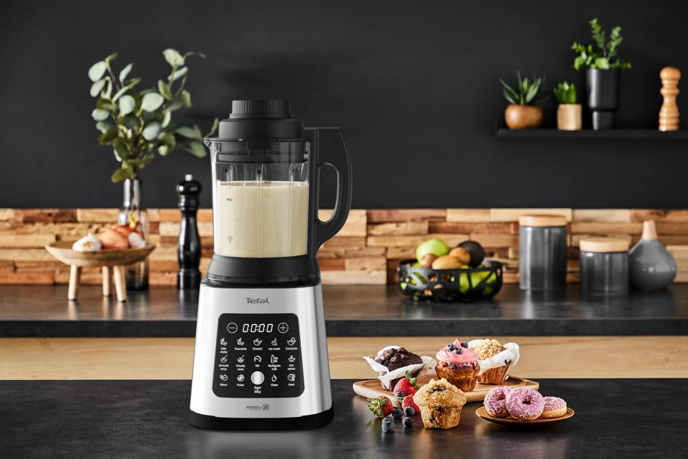 Een zilveren Tefal blender met een kan romige vloeistof op een aanrecht.