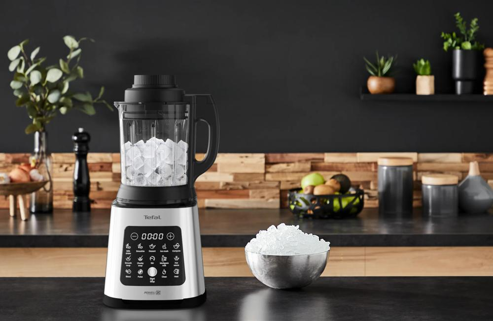 Een zilveren blender gevuld met ijsblokjes staat op een aanrecht.