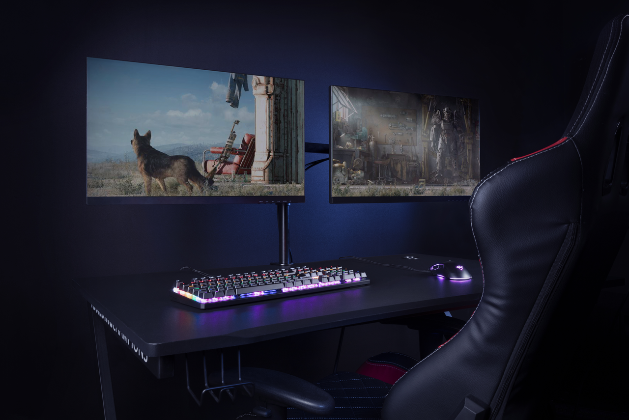 Eine Gaming-Einrichtung mit zwei Monitoren, die Spielszenen zeigen, einer Tastatur und einer Maus.