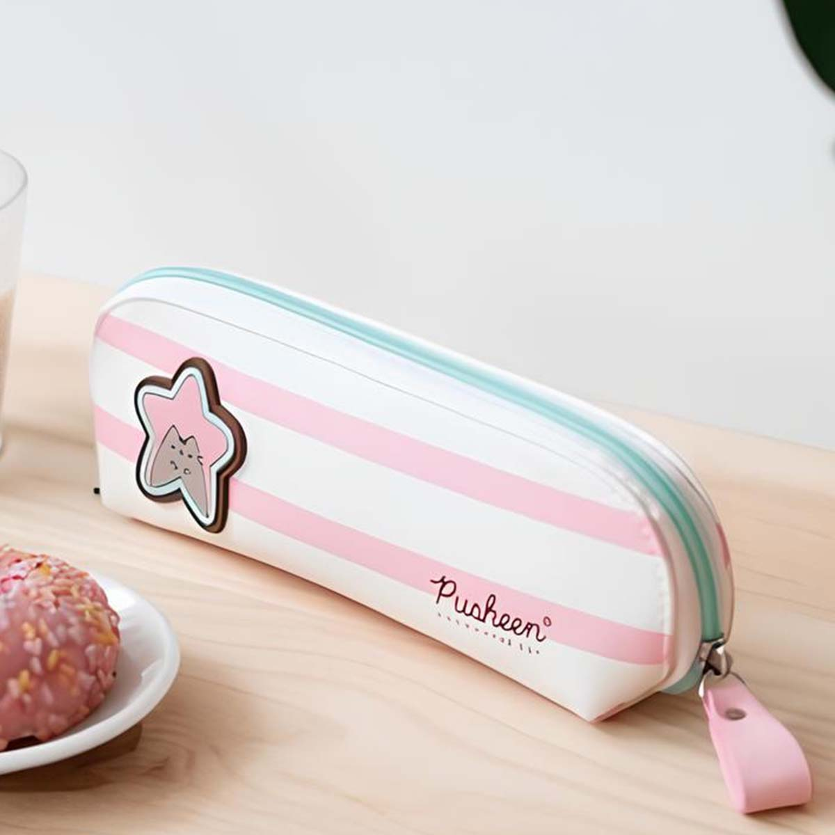 Ein weißes Federmäppchen mit rosa und hellblauen Streifen, mit einem Pusheen-Stern-Anhänger.