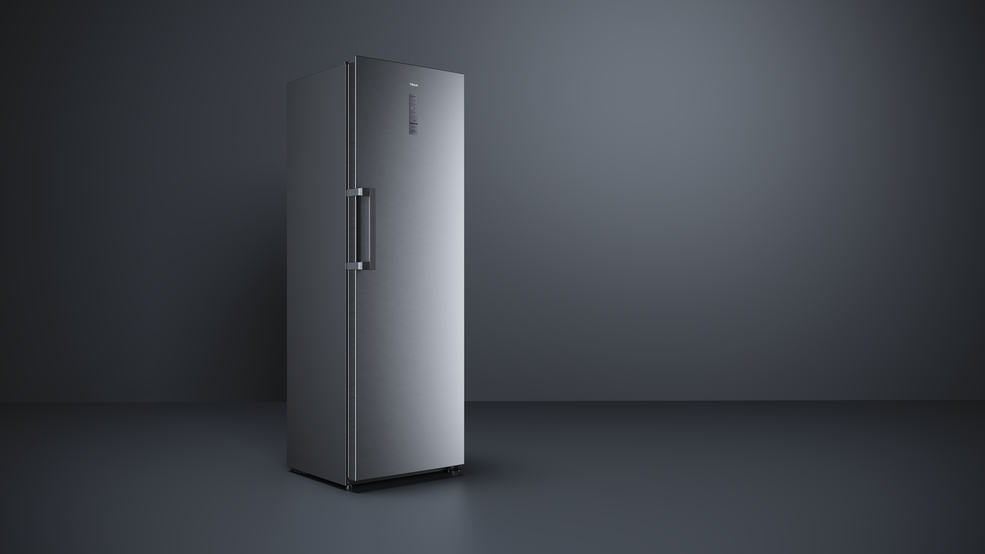 Un refrigerador plateado y elegante se encuentra sobre un suelo oscuro frente a un fondo oscuro.