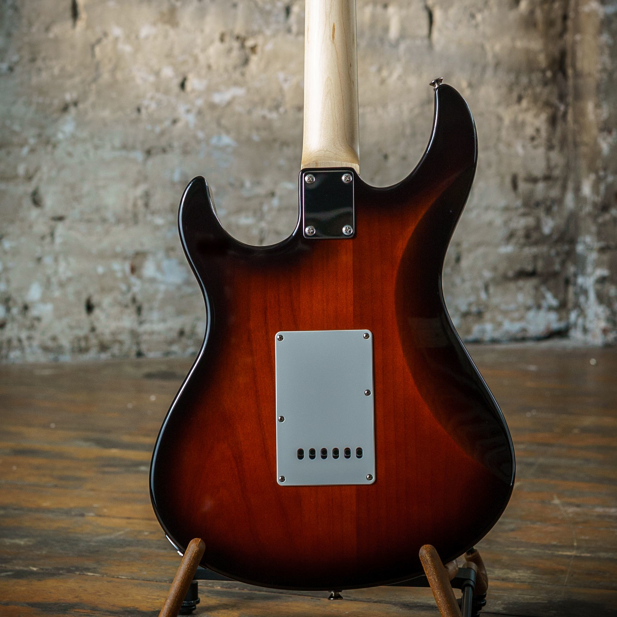 Rückseite einer E-Gitarre mit braunem Sunburst-Finish auf Holzboden.