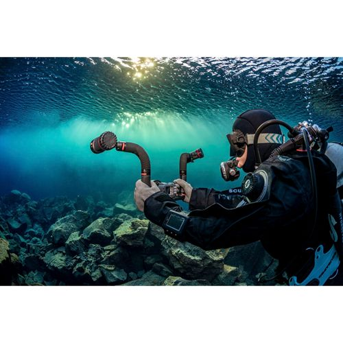 Ein Taucher unter Wasser hält eine Kamera mit zwei Armen und Lichtern.