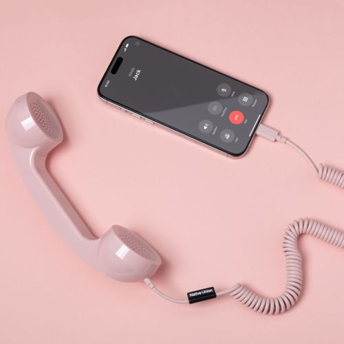 Un auricolare rosa è collegato via cavo a uno smartphone che mostra una chiamata in arrivo.