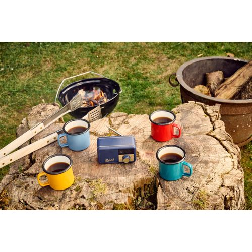 Quattro tazze colorate di caffè siedono su un ceppo d'albero accanto a una radio blu.