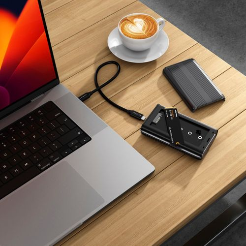 Un laptop, una tazza di caffè con cuore e un disco rigido esterno.