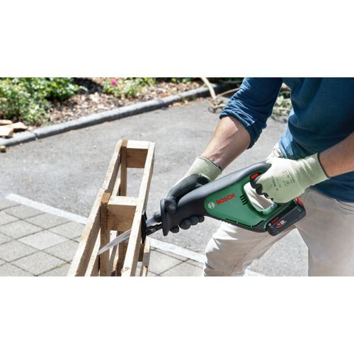 Person mit Handschuhen benutzt Säbelsäge an Holzpalette.