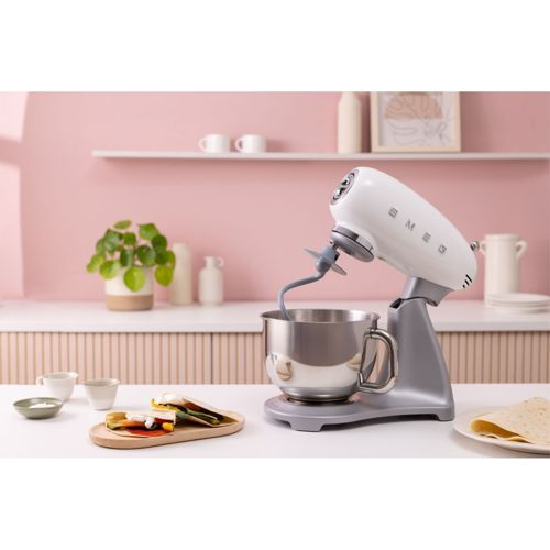 Un robot de cocina blanco con bol plateado y gancho amasador en una encimera.