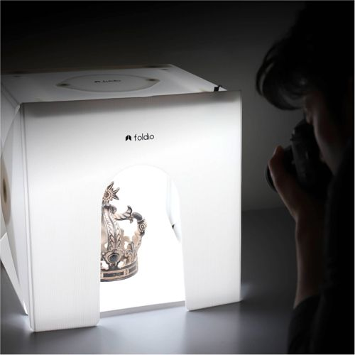 Eine Krone wird in einem Foldio-Fotostudio von einer Person mit einer Kamera fotografiert.