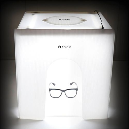 Ein weißer Lichtkasten zeigt eine Brille mit schwarzem Rand in einem Bogen.