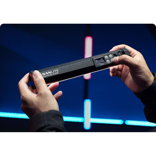 Une personne tient une lumière tubulaire noire Nanlite PavoTube 2 60X avec écran et commandes.