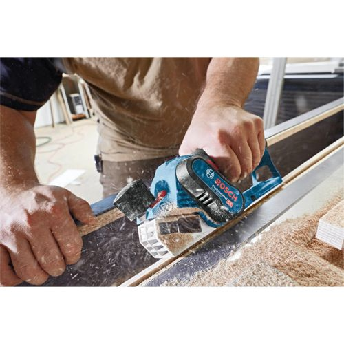 Un uomo usa una fresatrice per bordi Bosch blu per lavorare il legno.