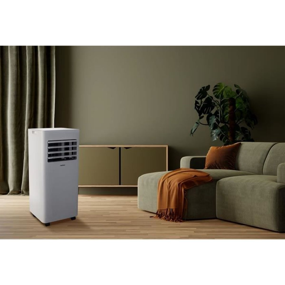 A white portable air conditioner sits in a living room next to a sofa.
