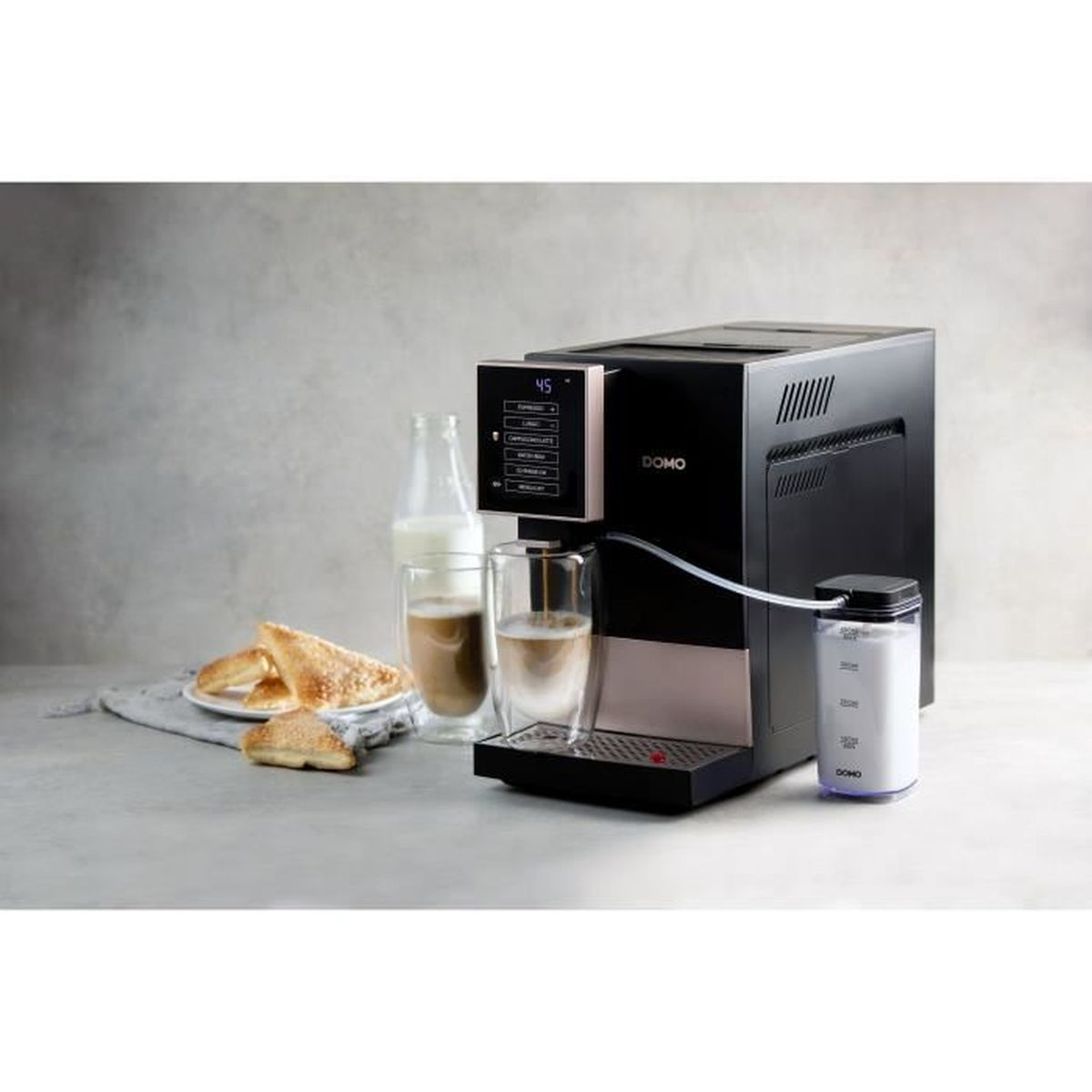 Macchina da caffè con caraffa del latte, due bicchieri e pasticcini su un tavolo.