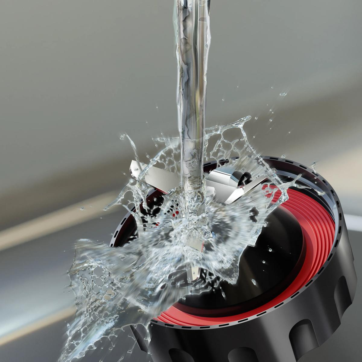L'acqua schizza sulle lame di un frullatore con corpo nero e rosso.