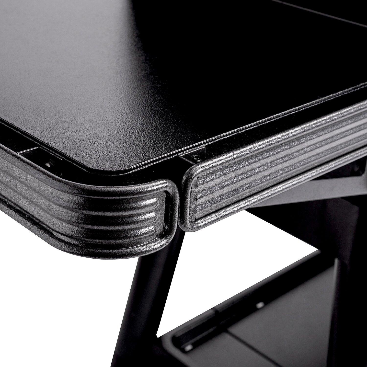 Mesa negra con borde acanalado y patas metálicas.