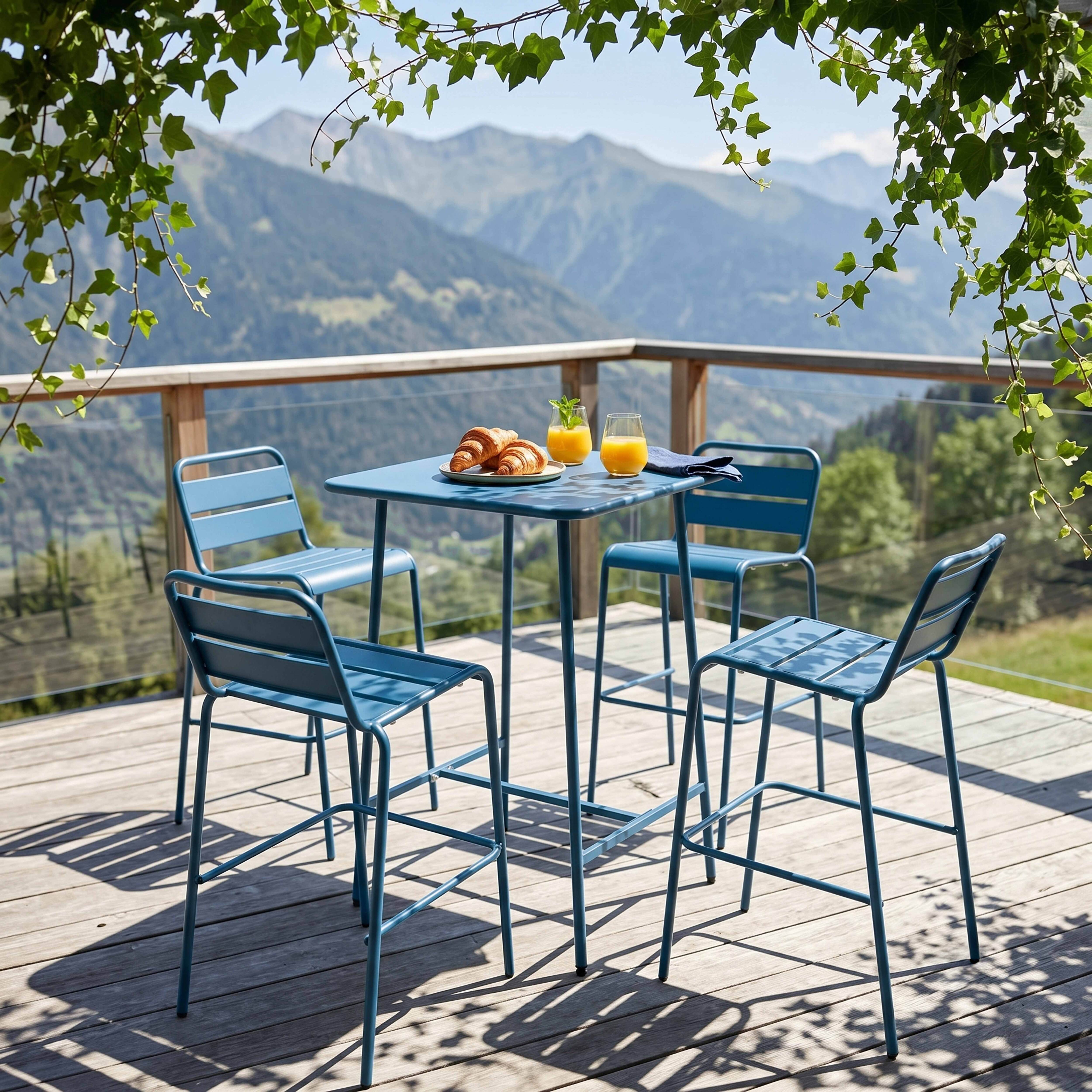 Ein blauer Tisch mit vier Stühlen auf einer Holzterrasse mit Bergkulisse.